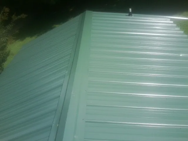 New green metal panels meeting at the ridge of a roof — Flat Roof Repair work by our crew in Seal Beach