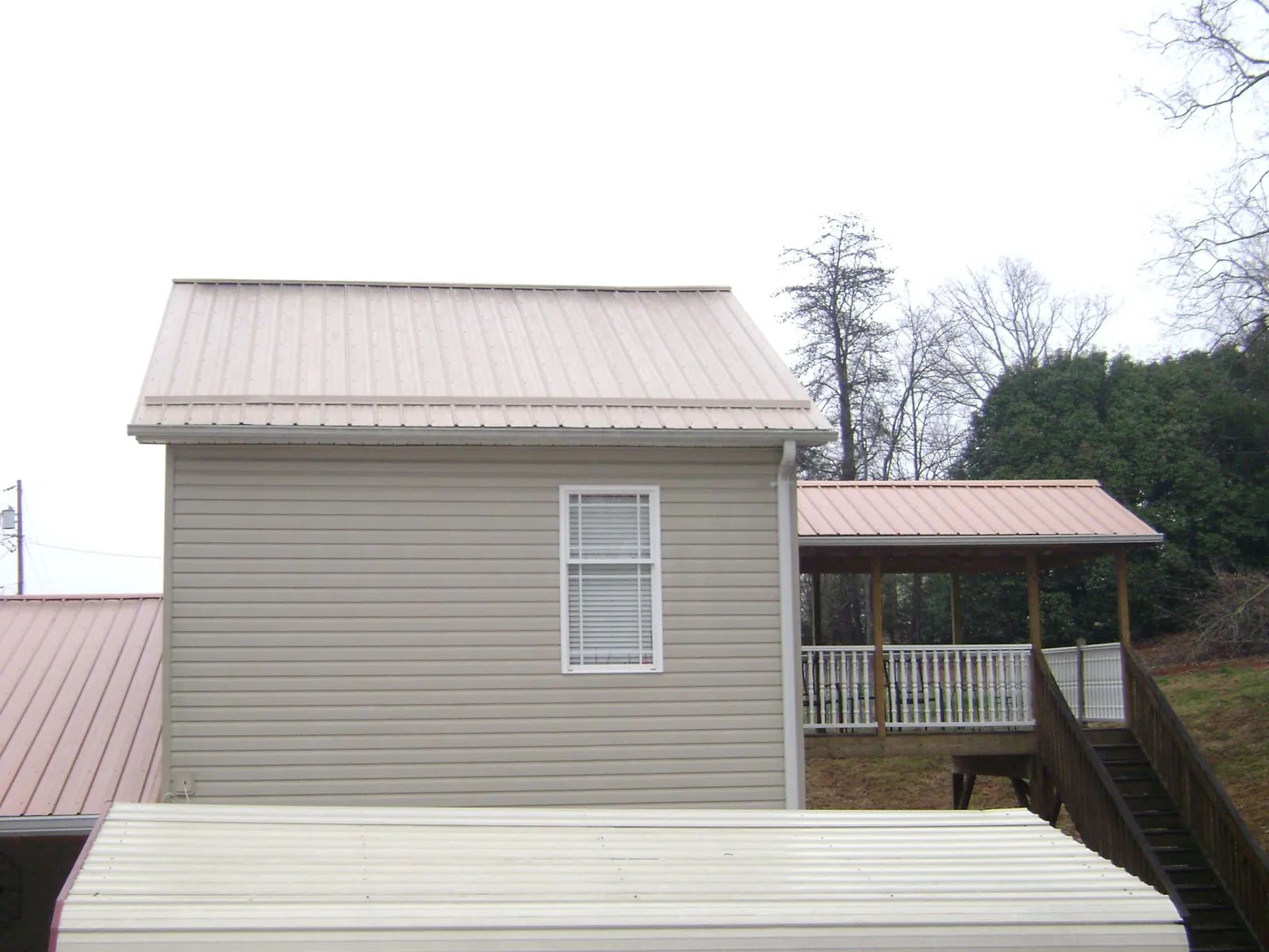 Tan metal roofs on a two story addition and attached porch, from a Roof Replacement job in Seal Beach