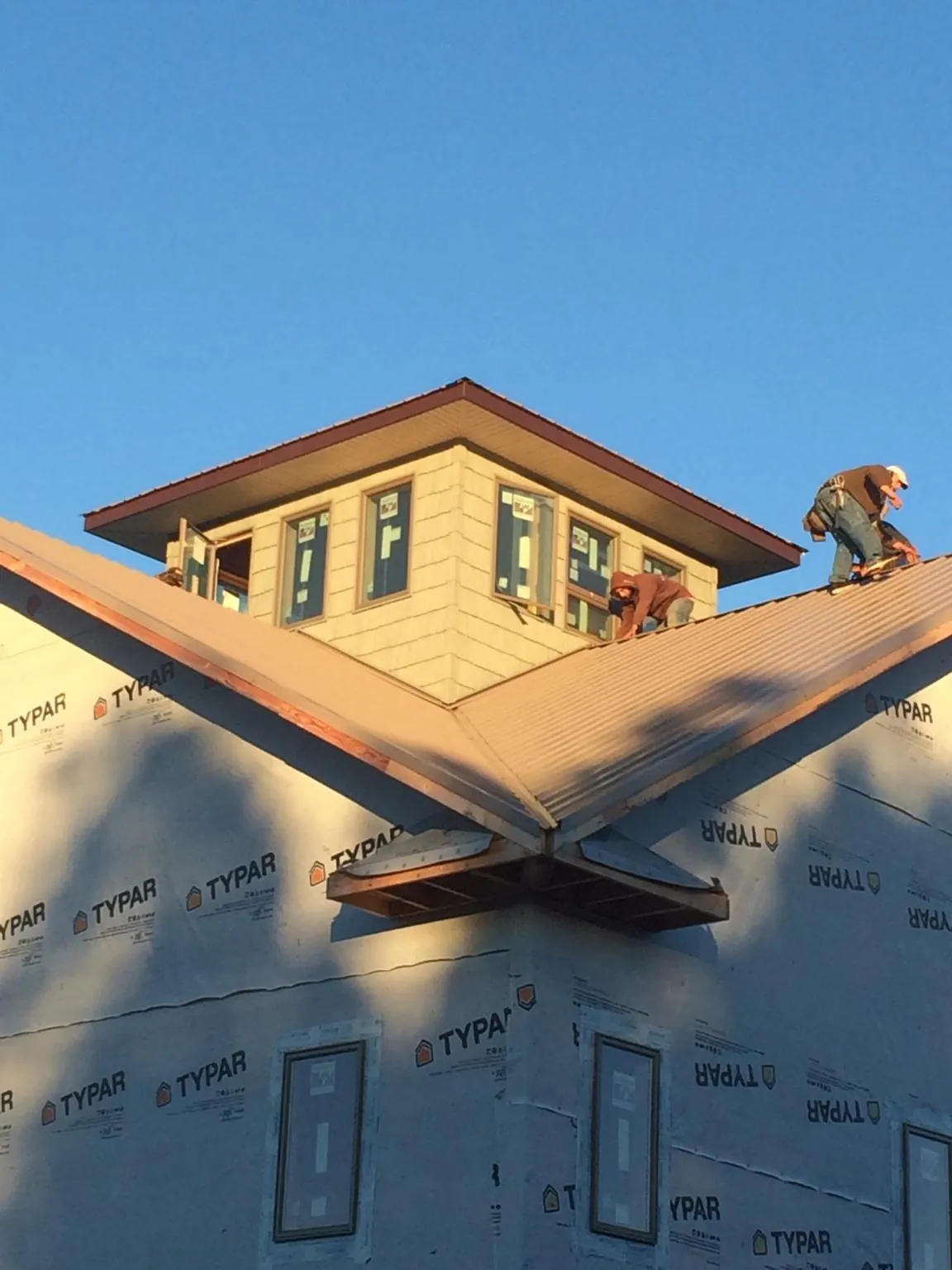 Roofers working around a rooftop cupola on a new metal roof at sunset — Roof Waterproofing in Seal Beach by Roofing Brothers